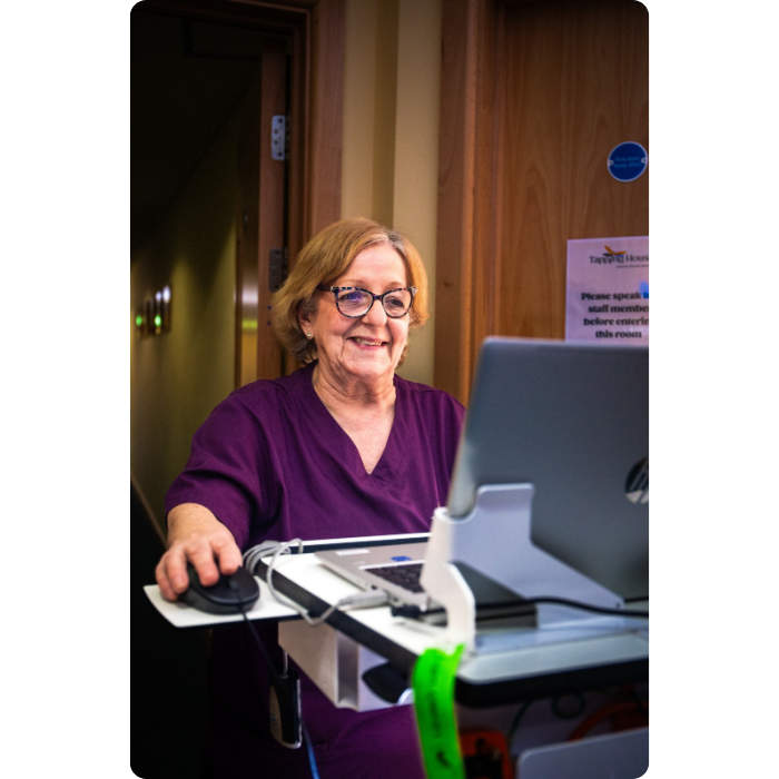 Tapping House Norfolk Hospice team member using laptop and mouse