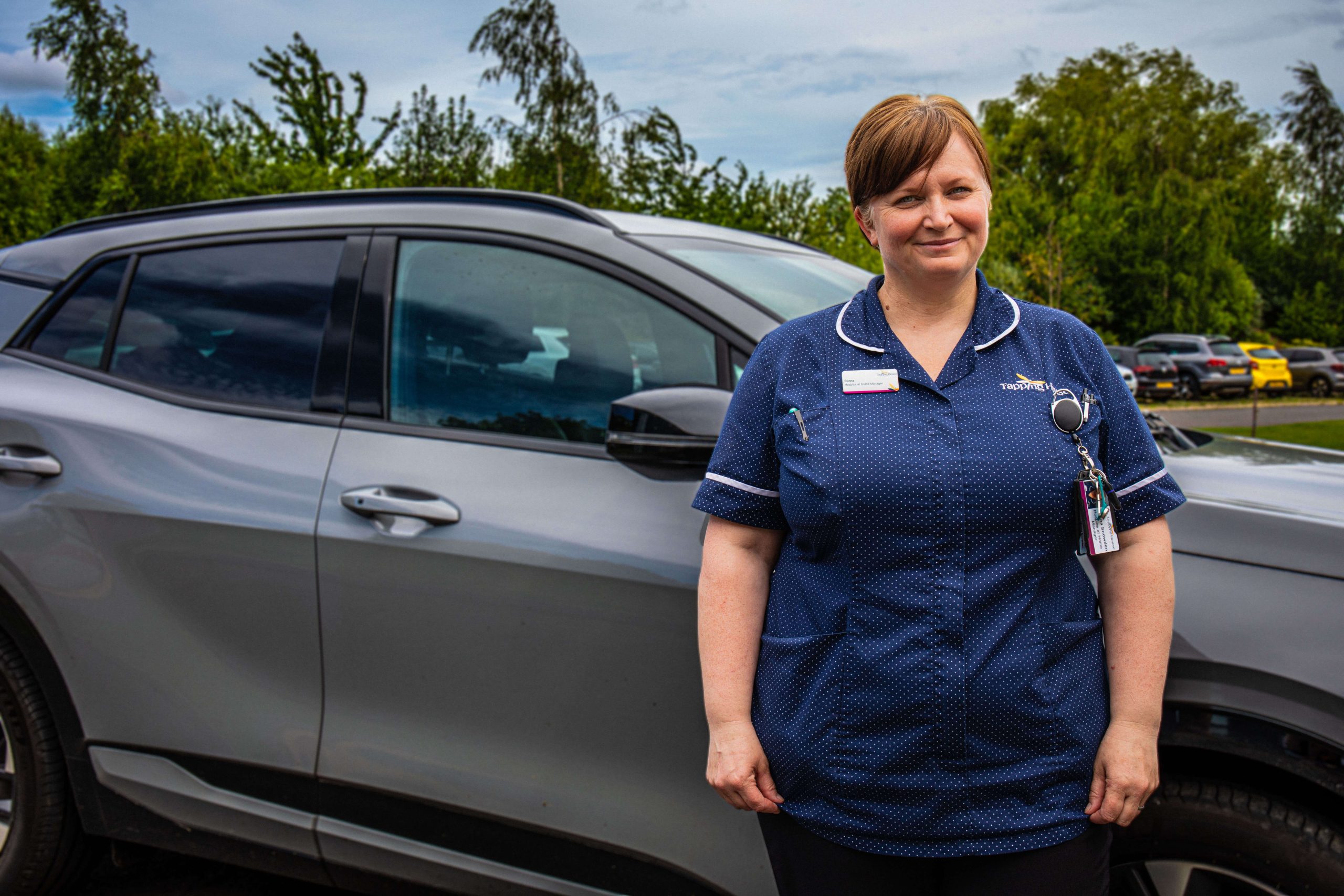 Donna Hospice at Home worker in front of car at Tapping House Norfolk Hospice Charity