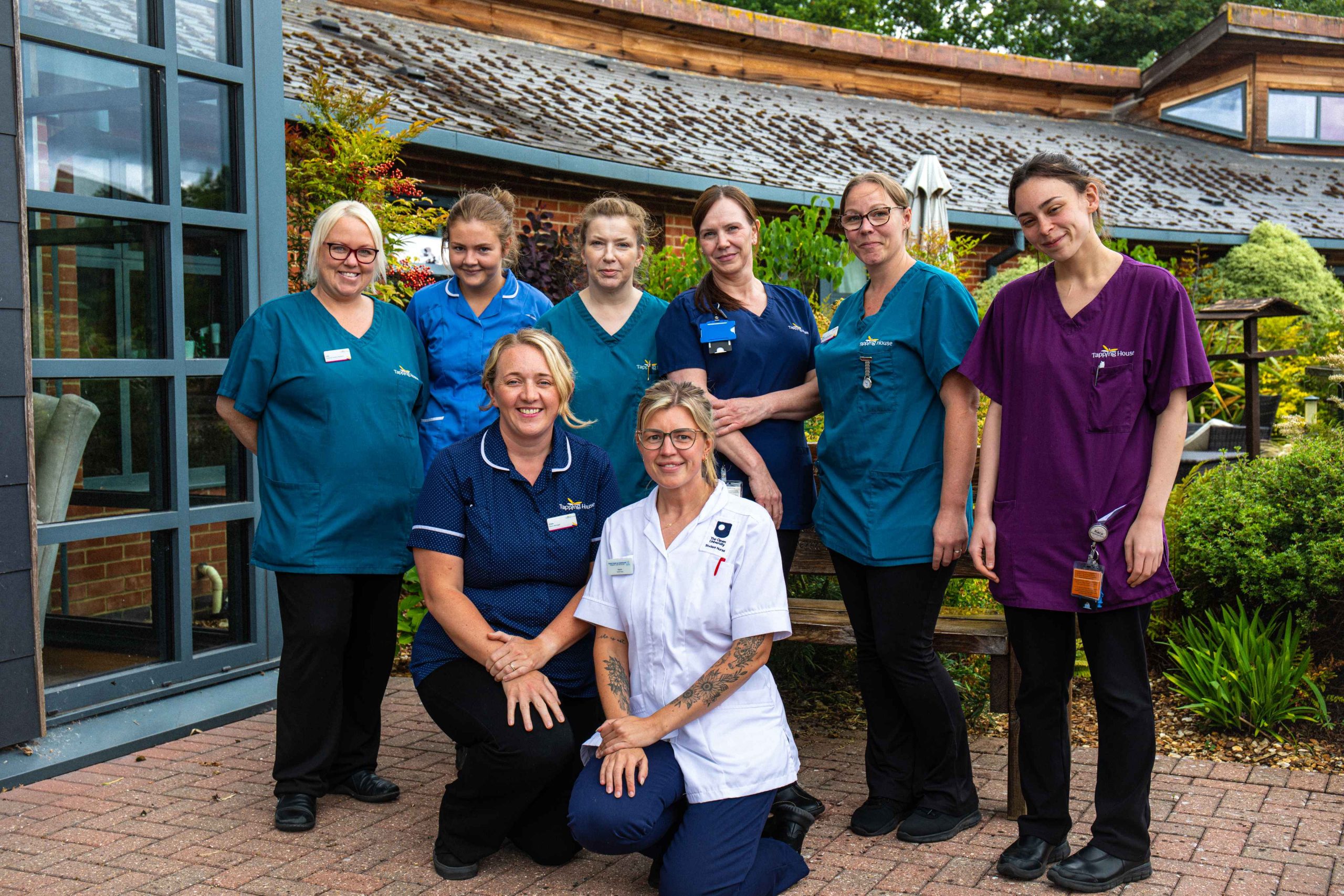 Staff photo of smiling team members outside Tapping House Norfolk Hospice Charity zoomed out